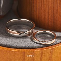 two wedding rings sitting on top of a wooden table