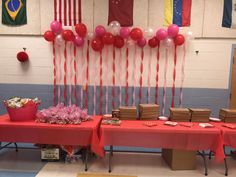 the table is set up with red and white balloons, books, and other items