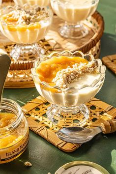 several desserts in glass dishes on a table with spoons and utensils