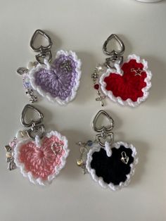 four crocheted heart shaped key chains on a table