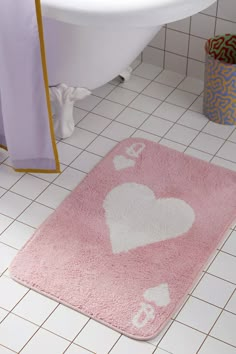 a pink rug with white hearts on it in a bathroom next to a bathtub