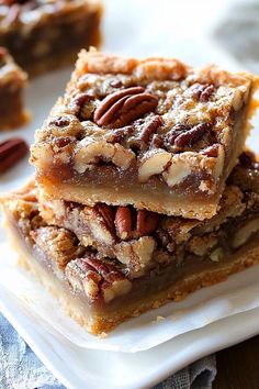 pecan bars stacked on top of each other on a white plate with blue napkin