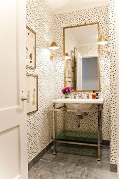 a white sink sitting under a bathroom mirror next to a wall covered in black and white dots