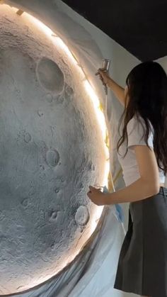 a woman is painting the moon with white paint