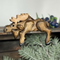 a wooden moose figurine sitting on top of a shelf next to a pine tree