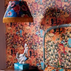 a room with colorful wallpaper and a lamp on the side table next to it