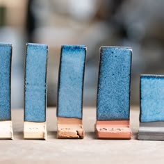 four small blue vases sitting on top of a wooden table next to each other