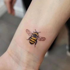 a small tattoo of a bee on the ankle, with black and yellow stripes around it