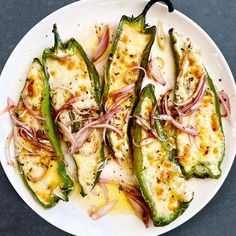 a white plate topped with green peppers covered in cheese and onions on top of a table