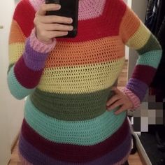 a woman taking a selfie in front of a mirror wearing a multicolored sweater