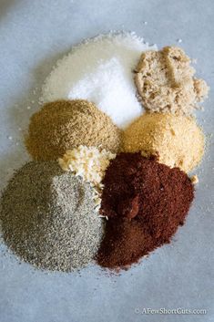 four different types of spices on a white table top with some brown and one red