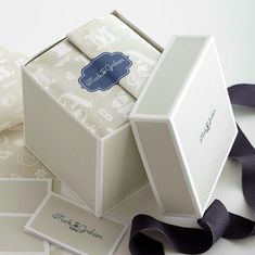 a white box with black ribbon on top of it and some cards in the bottom