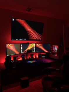 a room with two monitors and red lights on the wall, in front of a large flat screen tv