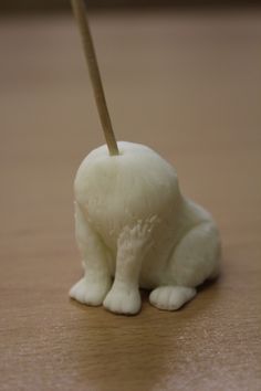 a white cat figurine sitting on top of a wooden table next to a toothbrush