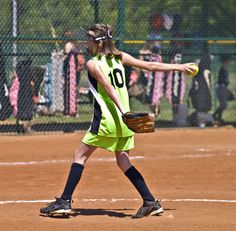 a girl in a softball uniform throwing a ball