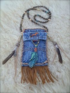 a cell phone case made out of jeans and beads with feathers hanging from the back