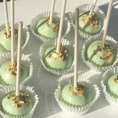 there are many green desserts with gold decorations on the top one is chocolate and has white sticks sticking out of it