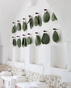 a room with white furniture and green leaves hanging on the wall above it's windows