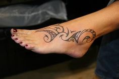 a woman's foot with a tattoo design on the top of her left leg