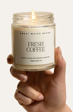 a hand holding a candle that says fresh coffee in front of a white background with the words sweet water decor on it