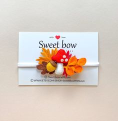 a small red and yellow flower with leaves on it's head is sitting in front of a white card