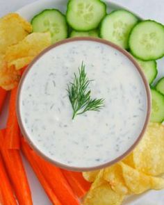 a white plate topped with carrots, cucumber and chips