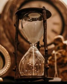 an hourglass sitting on top of a table next to a clock and other items