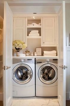 a washer and dryer in a small room next to each other with white cabinets