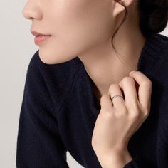 a woman wearing a black sweater with a ring on her left hand and an earring on her right