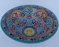 a colorful bowl is sitting on the table with an ornate design in it's center