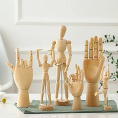 several wooden hand puppets on a table next to each other with one holding the other's hand