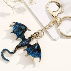 a blue dragon shaped keychain sitting on top of a white table next to a pair of scissors