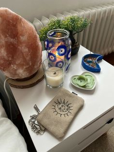 an assortment of items sitting on a table next to a candle and potted plant