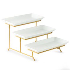 two white trays with gold legs are stacked on each other