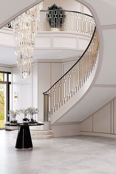 an elegant staircase with chandelier and table in the middle, surrounded by marble flooring