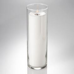 a white candle is in a glass vase