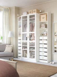 a living room filled with furniture and lots of white storage space next to a window