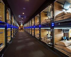 a long row of bunk beds in a room filled with lots of pillows and blankets