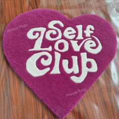 a heart shaped towel with the words self love club on it sitting on a table