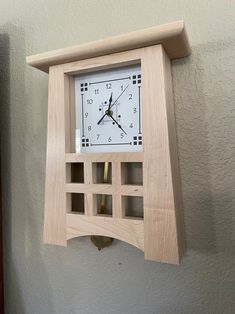 a wooden clock mounted to the side of a wall with squares on it and a pendulum