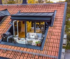 an aerial view of the roof of a house with red tiles and black metal windows