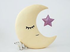 a stuffed polar bear sitting next to a crescent moon with a pink star hanging from it's side