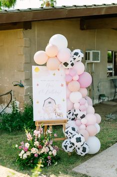 a sign with balloons attached to it in front of a house that has a cow theme on it