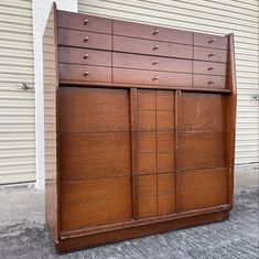 a large wooden dresser sitting in front of a garage door on the side of a building