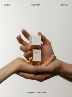 two hands holding a small bottle of perfume in front of a white background with the caption visible