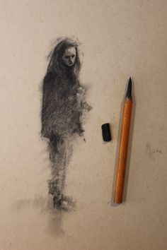 a pencil is next to a drawing of a person with long hair and a creepy face