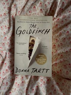 the goldfinch by donna tart on a bed with pink and white sheets