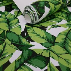 a green and white tropical print wallpaper with leaves on the bottom right hand corner