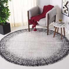 a white and black rug in a living room next to a chair with a red blanket on it