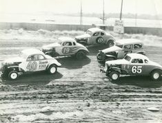 four cars are parked in the dirt with numbers on them